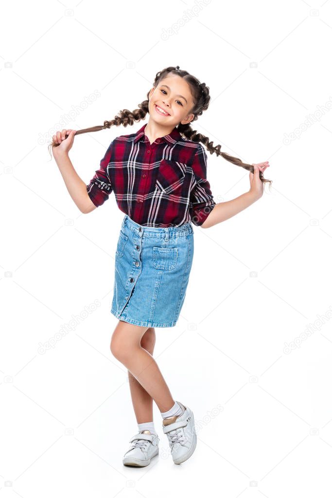 schoolchild holding long braids and looking at camera isolated on white