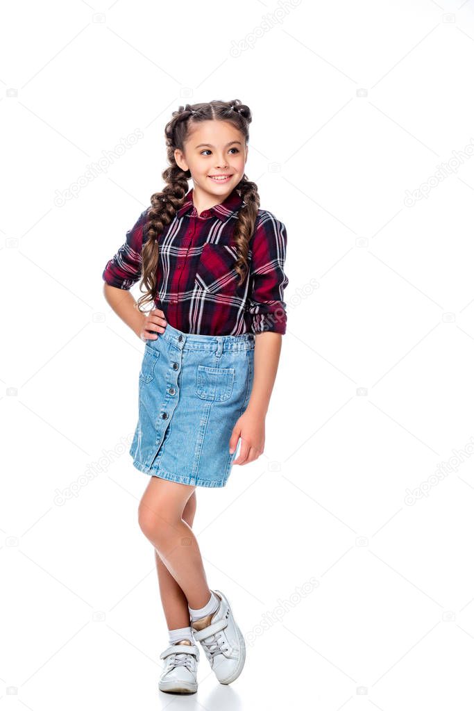schoolchild in denim skirt and checkered shirt posing and looking away isolated on white