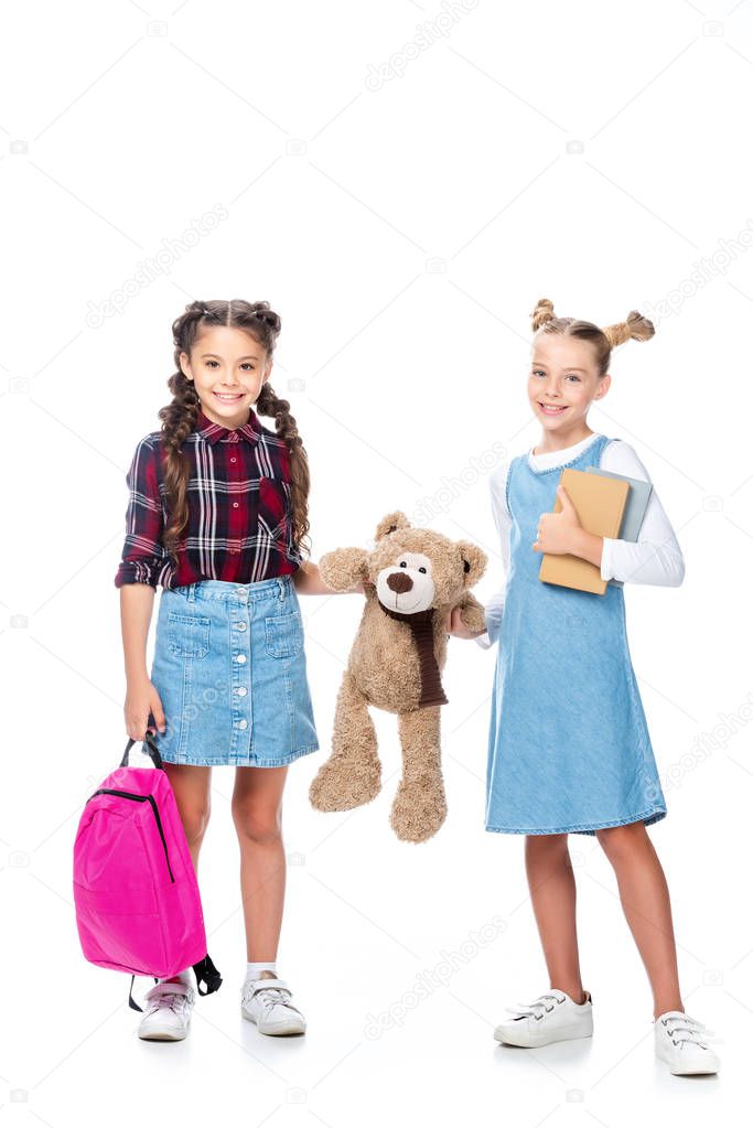 schoolchildren holding teddy bear and looking at camera isolated on white