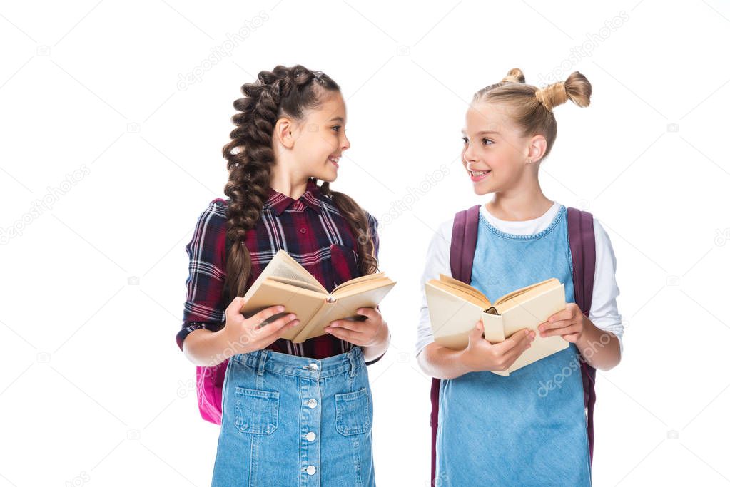 schoolchildren holding open books and looking at each other isolated on white