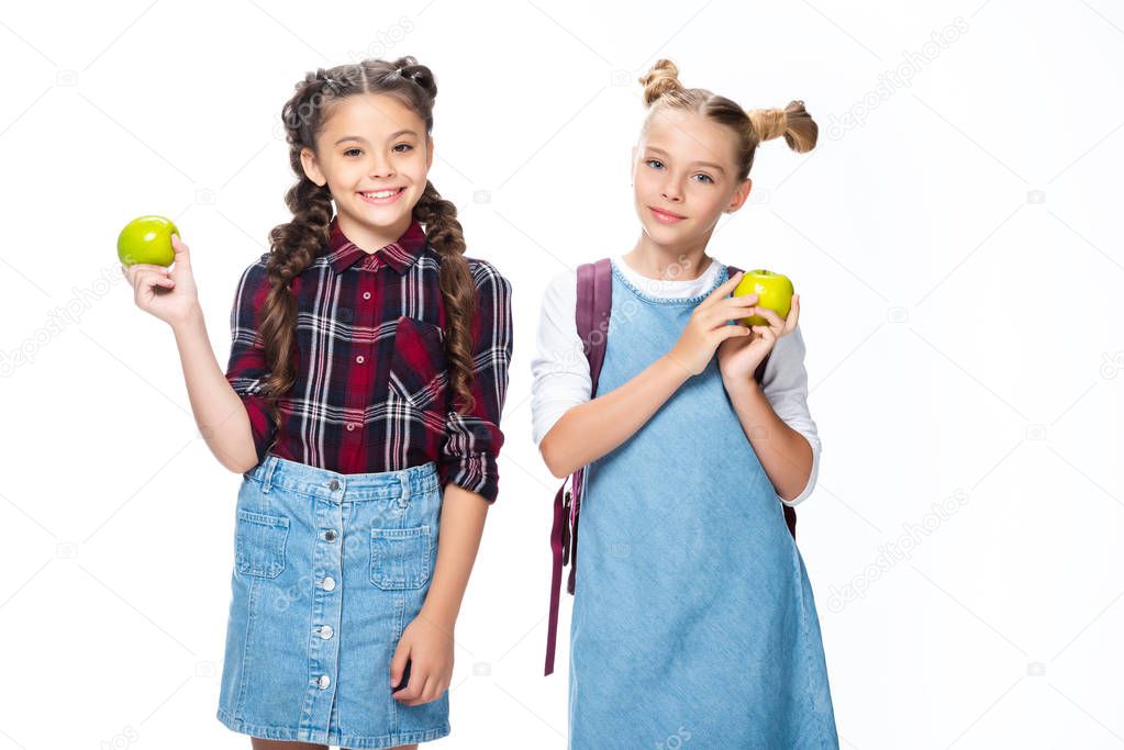smiling schoolchildren holding apples and looking at camera isolated on white