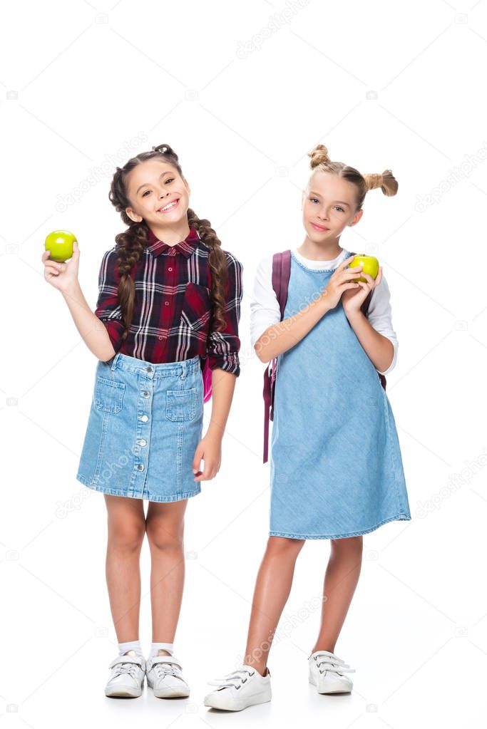 schoolchildren holding apples and looking at camera isolated on white