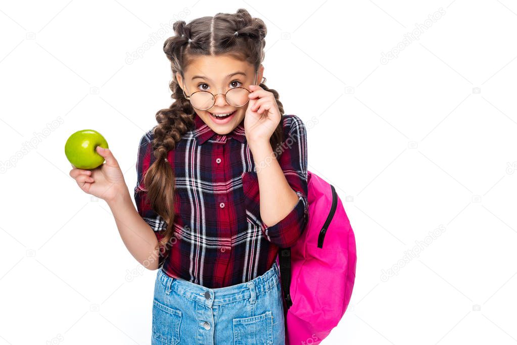 schoolchild holding ripe apple and looking at camera above glasses isolated on white