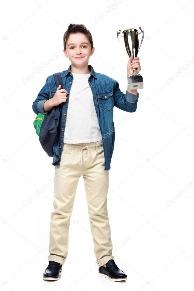 schoolboy with backpack holding silver winner cup isolated on white