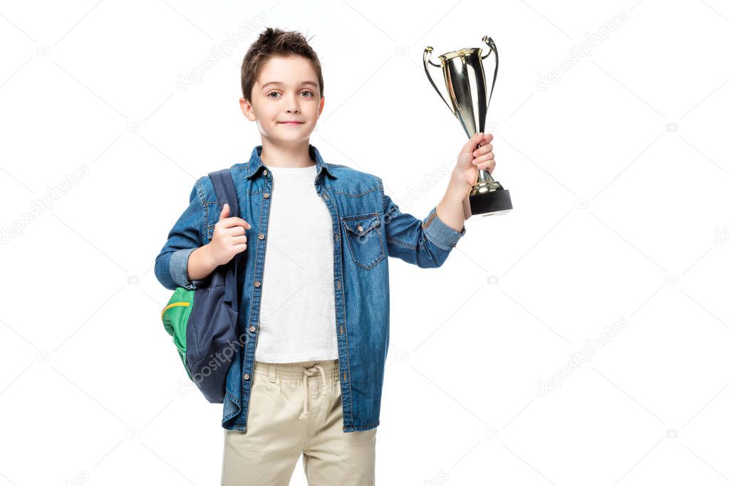 adorable schoolboy with backpack holding winner cup isolated on white