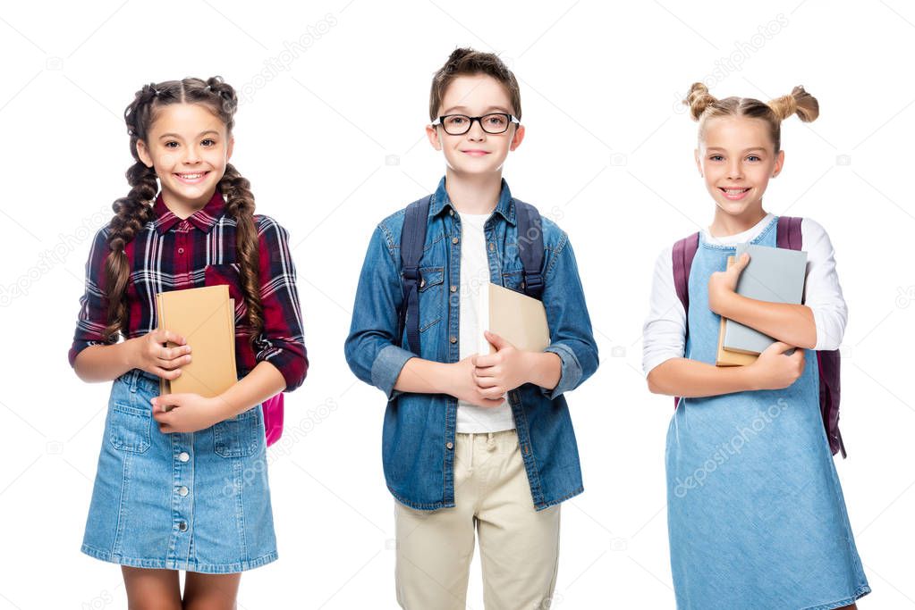 three smiling classmates holding books and looking at camera isolated on white
