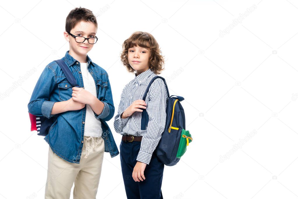 two schoolboys with backpacks looking at camera isolated on white