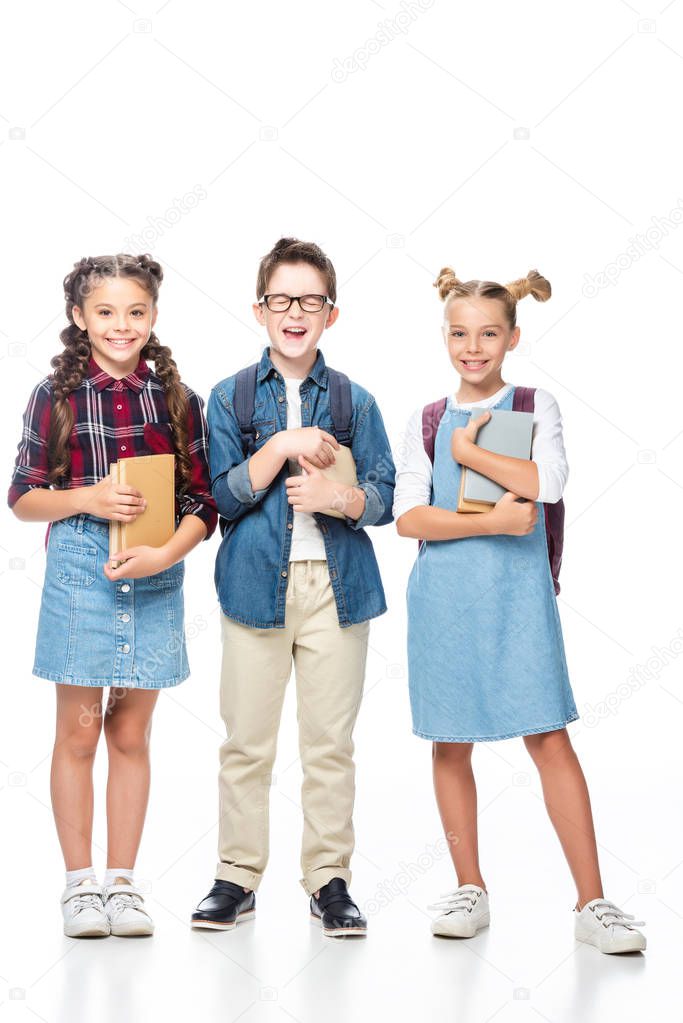 happy classmates holding books and looking at camera isolated on white