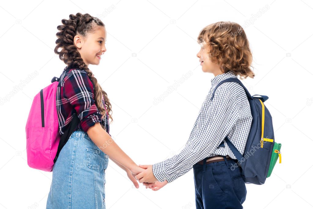 side view of classmates holding hands and looking at each other isolated on white
