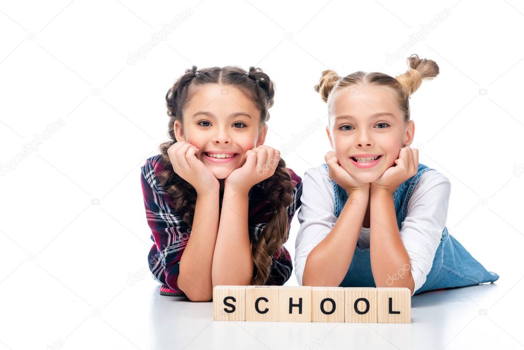 schoolchildren lying near wooden cubes with word school isolated on white 