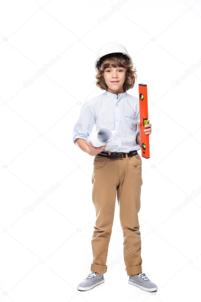 schoolboy in costume of architect and helmet holding blueprints and bubble level isolated on white