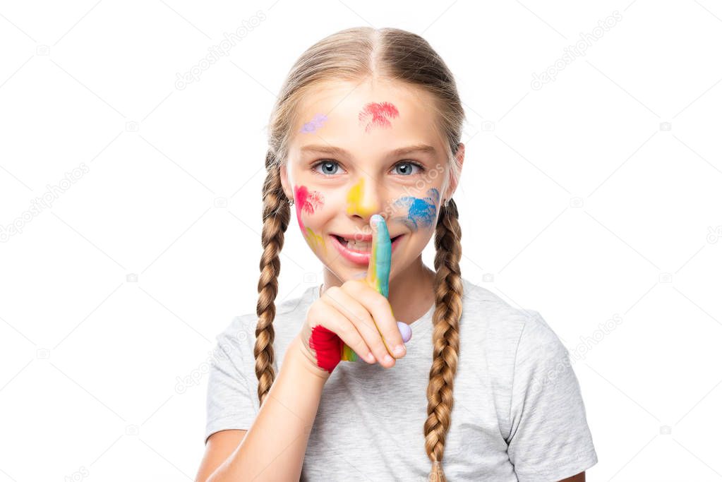 schoolchild with paints on face showing silence gesture isolated on white