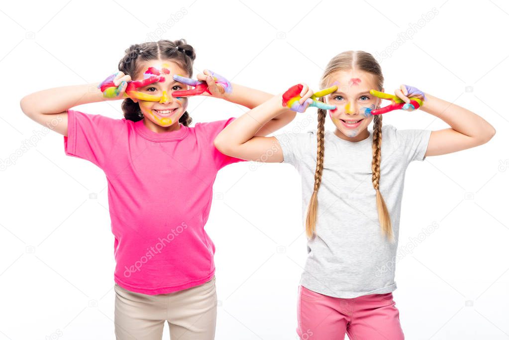 smiling schoolchildren looking through painted fingers isolated on white