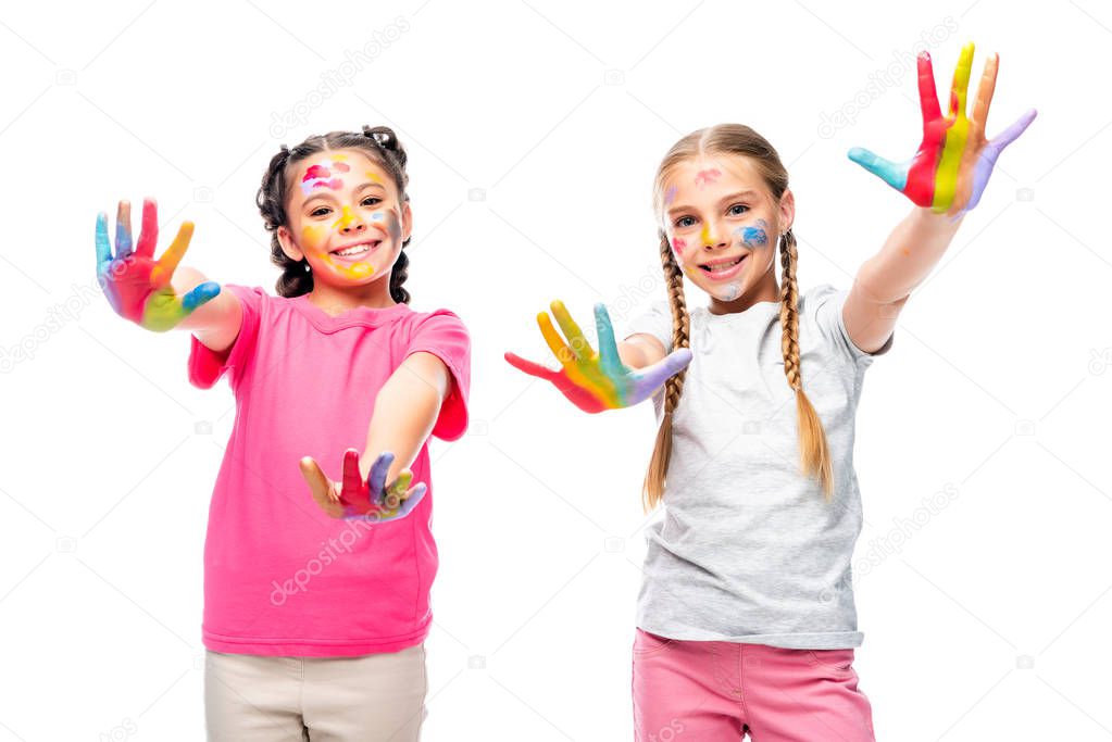 schoolchildren showing painted colorful hands and looking at camera isolated on white
