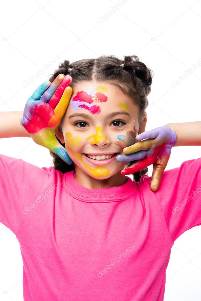 adorable schoolchild touching face with painted hands isolated on white