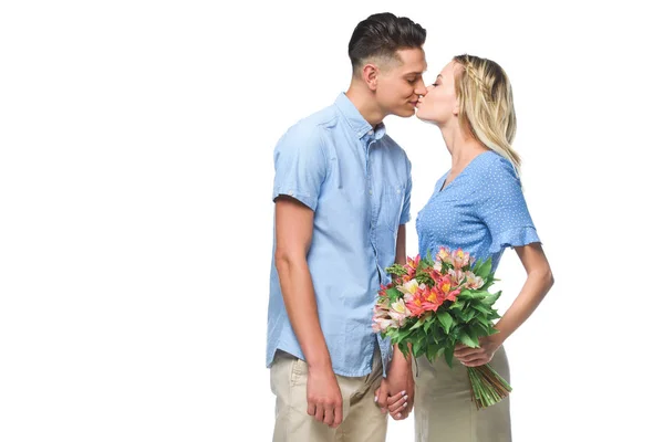 couple in blue shirts kissing isolated on white, girlfriend holding bouquet