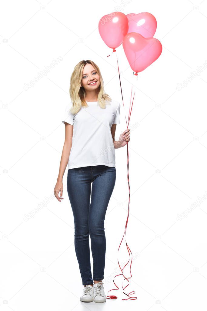 beautiful girl in casual clothes holding bundle of heart shaped balloons isolated on white