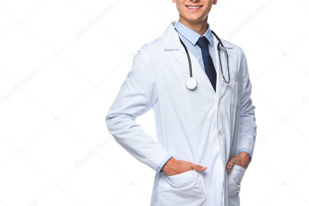 cropped shot of young doctor with hands in pockets of medical coat isolated on white
