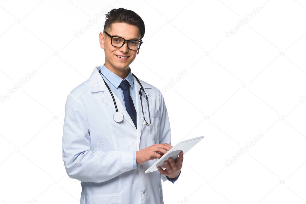 handsome young doctor using tablet and looking at camera isolated on white