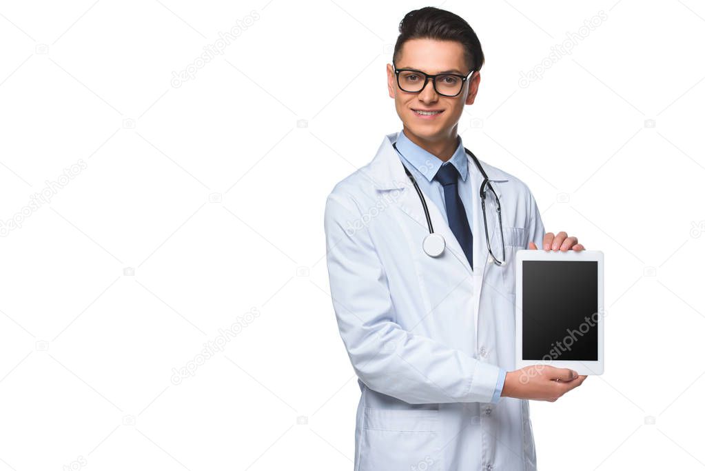 smiling young doctor holding tablet with blank screen isolated on white