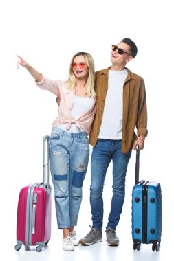 young travelling couple with suitcases pointing somewhere isolated on white clipart