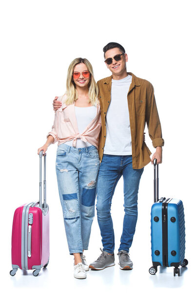 happy travelling couple with suitcases looking at camera isolated on white