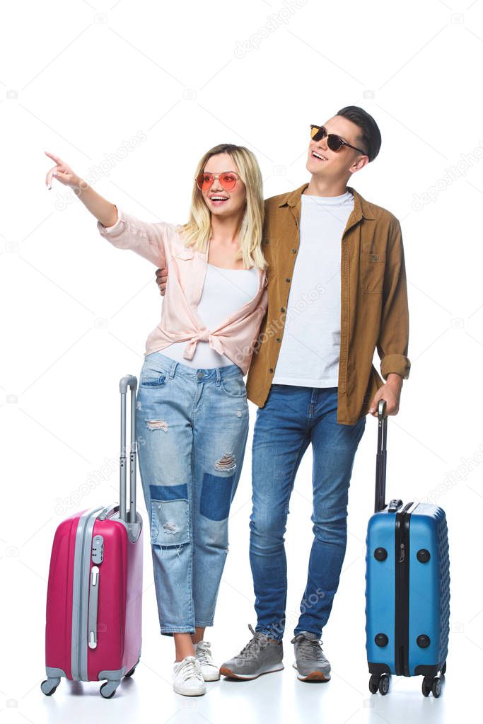 young travelling couple with suitcases pointing somewhere isolated on white