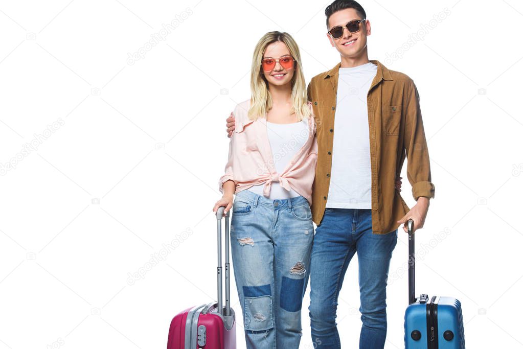 young smiling couple with suitcases looking at camera isolated on white