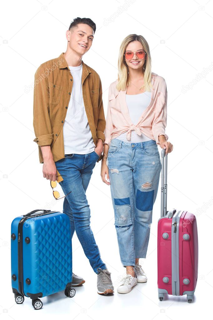 young travelling couple with suitcases looking at camera isolated on white