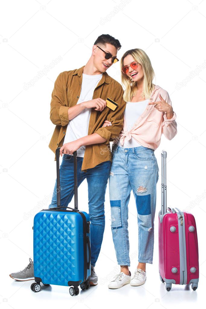 young travelling couple with suitcases and credit card isolated on white
