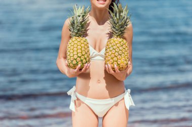 Kırpılan beyaz bikini taze ananas denize yakın tutan ince kız görünümünü