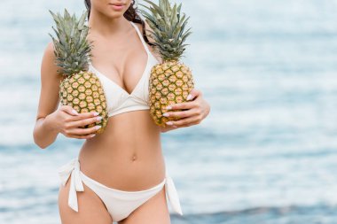 çekici kadın beyaz bikini taze ananas tutarak kısmi görünümünü 