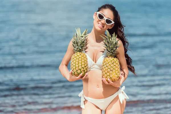 Hermosa Mujer Sonriente Bikini Gafas Sol Sosteniendo Piñas Frescas Cerca — Foto de stock gratuita