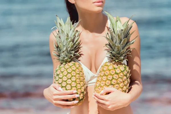 妇女在白色泳装的部分看法在海附近举行新鲜的菠萝 — 免费的图库照片