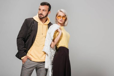 couple of models in stylish autumn outfits posing on grey background  clipart