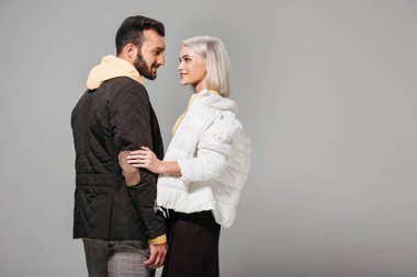 gri arka plan üzerinde izole birbirlerine bakarak sonbahar kıyafetleri modelleri şık çift yan görünüm  