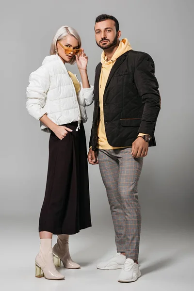 fashionable couple of models in autumn outfits posing on grey background