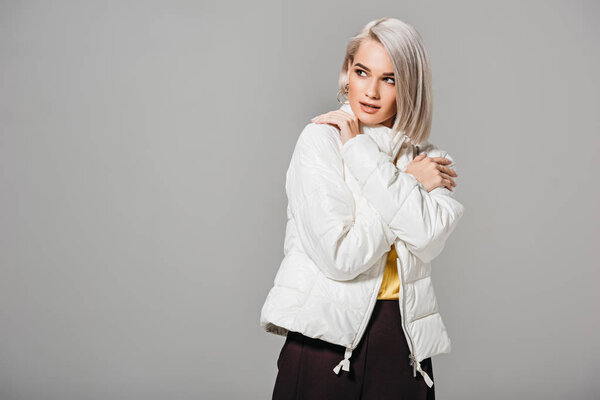 attractive young woman posing in white jacket isolated on grey background 