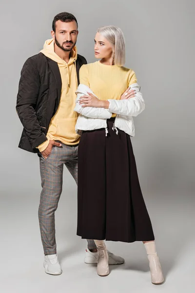年轻时尚女性模型与交叉胳膊站立与男朋友在灰色背景 — 图库照片