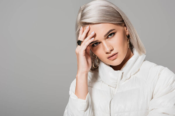 серьезная молодая модель, позирующая и смотрящая на камеру изолированно на сером фоне
 