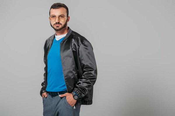 уверенный в себе человек в осеннем наряде позирует с руками в карманах изолированы на сером фоне
 