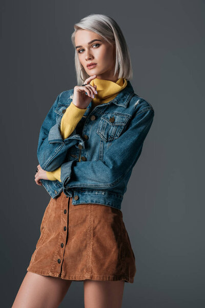 fashionable model posing in turtleneck, trendy corduroy skirt and jeans jacket, isolated on grey