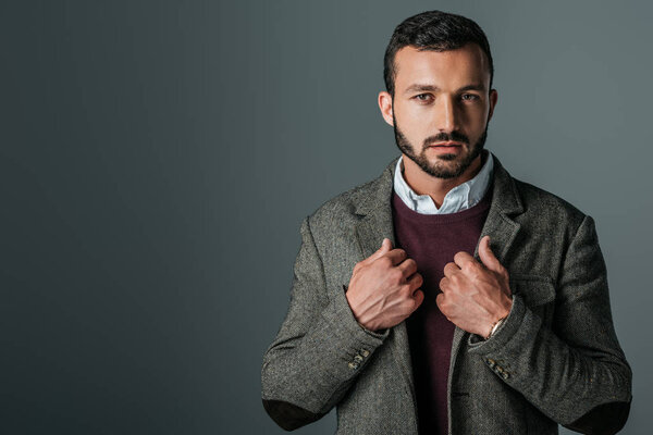 handsome stylish man posing in trendy tweed jacket, isolated on grey