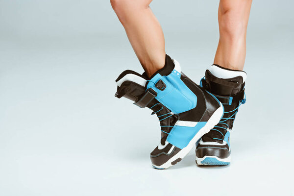Cropped image of sportswoman in ski boots, on grey