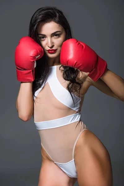 sexy boxer in white swimwear and boxing gloves isolated on grey