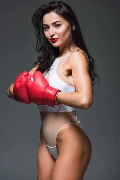 sexy athletic woman in white leotard and boxing gloves isolated on grey