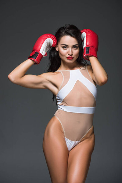 sexy sportive woman posing in white swimwear and boxing gloves isolated on grey 