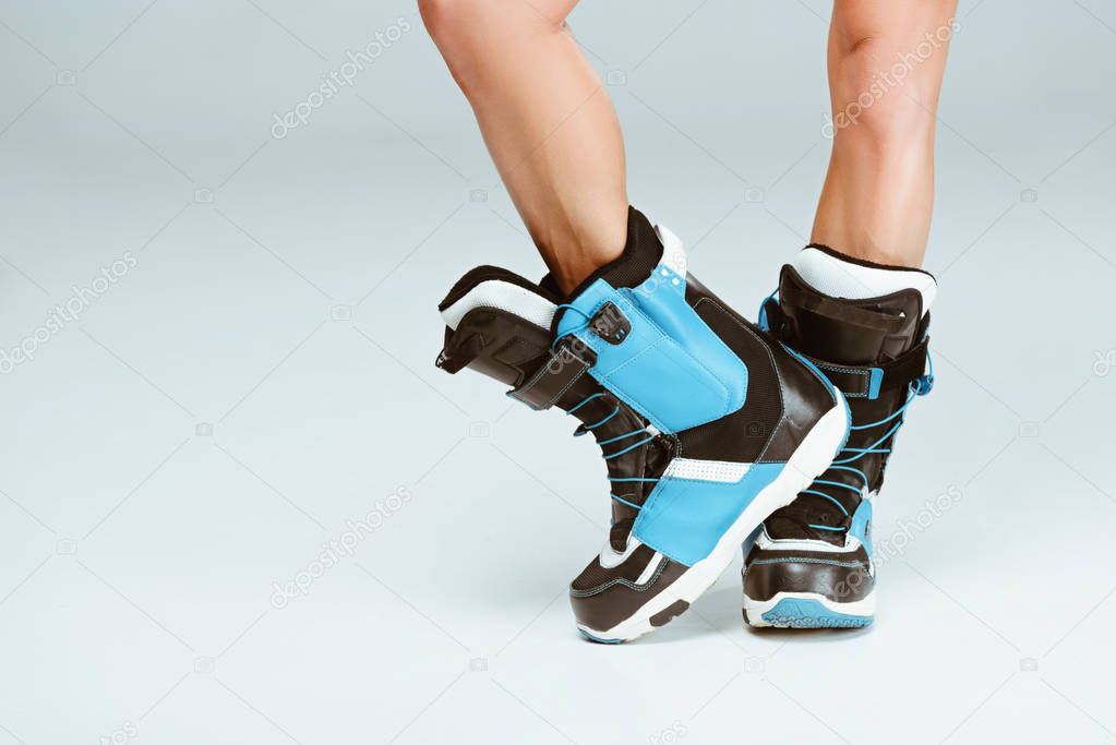 Cropped image of sportswoman in ski boots, on grey