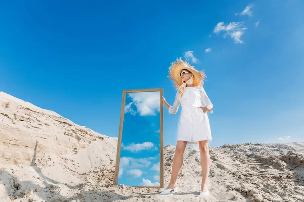 穿着白色衣服和草帽的时尚模特在沙丘上镜子附近 — 图库照片