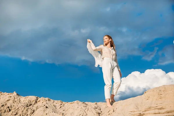 砂丘の上を歩いての絹のスカーフと白いのトレンディな服の魅力的なファッショナブルなモデル — ストック写真
